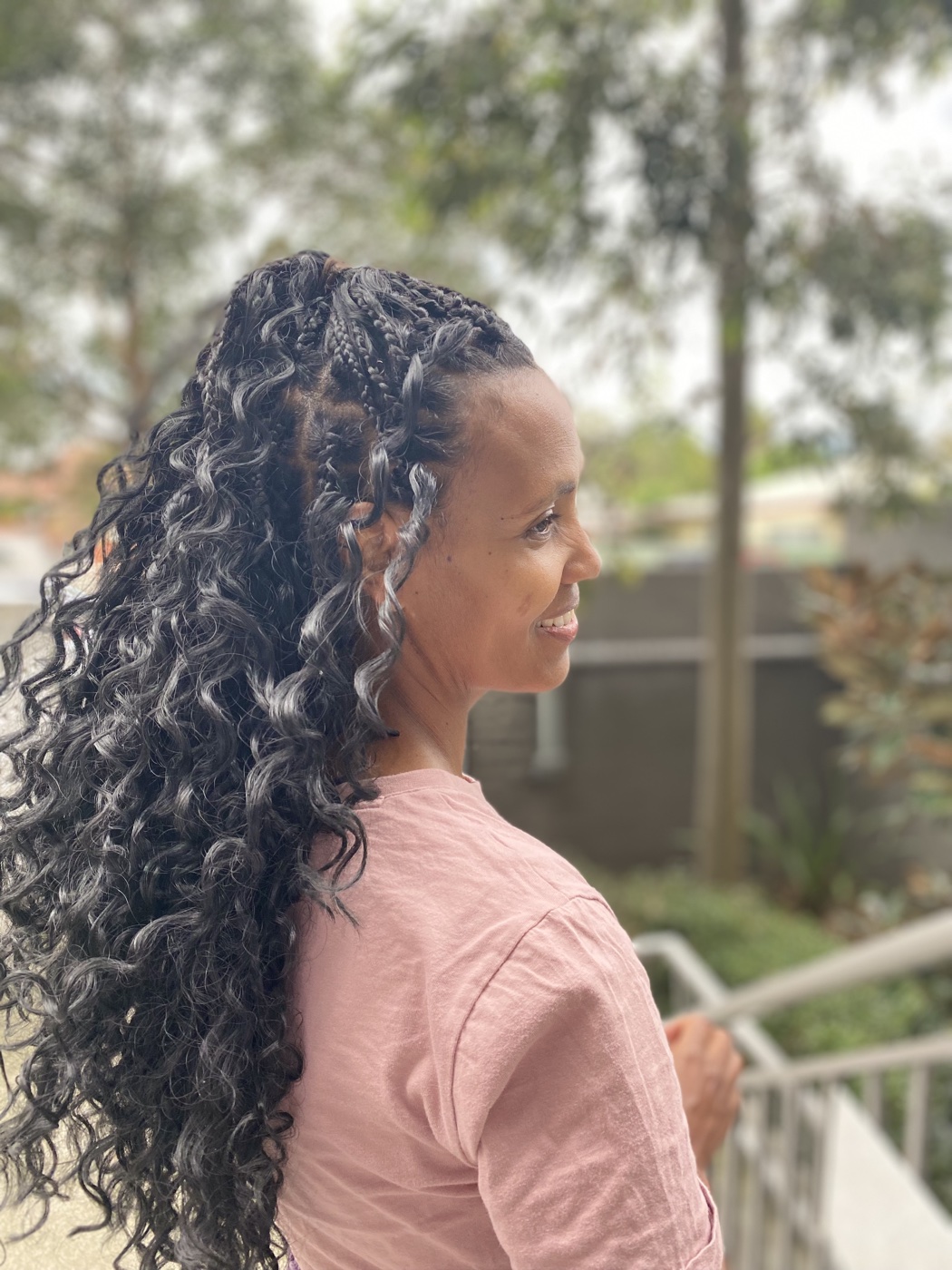 Long knotless braids with soft curly ends, photographed outdoors.