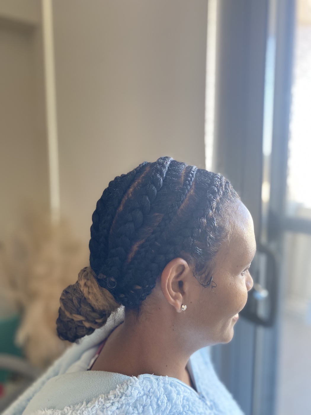 Stitch braids gathered into a low bun, side profile in natural light.